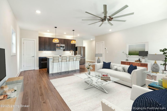 living area with recessed lighting, baseboards, a ceiling fan, and hardwood / wood-style flooring