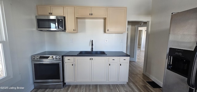 kitchen with dark wood finished floors, dark countertops, visible vents, appliances with stainless steel finishes, and a sink