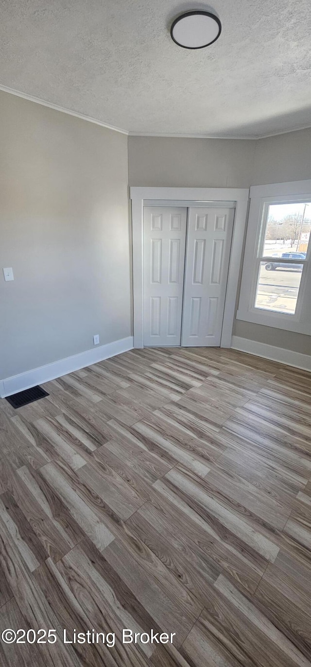 unfurnished bedroom featuring baseboards, a textured ceiling, visible vents, and a closet