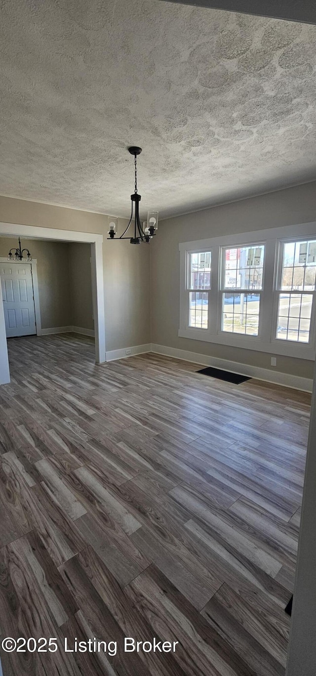 unfurnished dining area with a chandelier, dark wood-type flooring, and baseboards