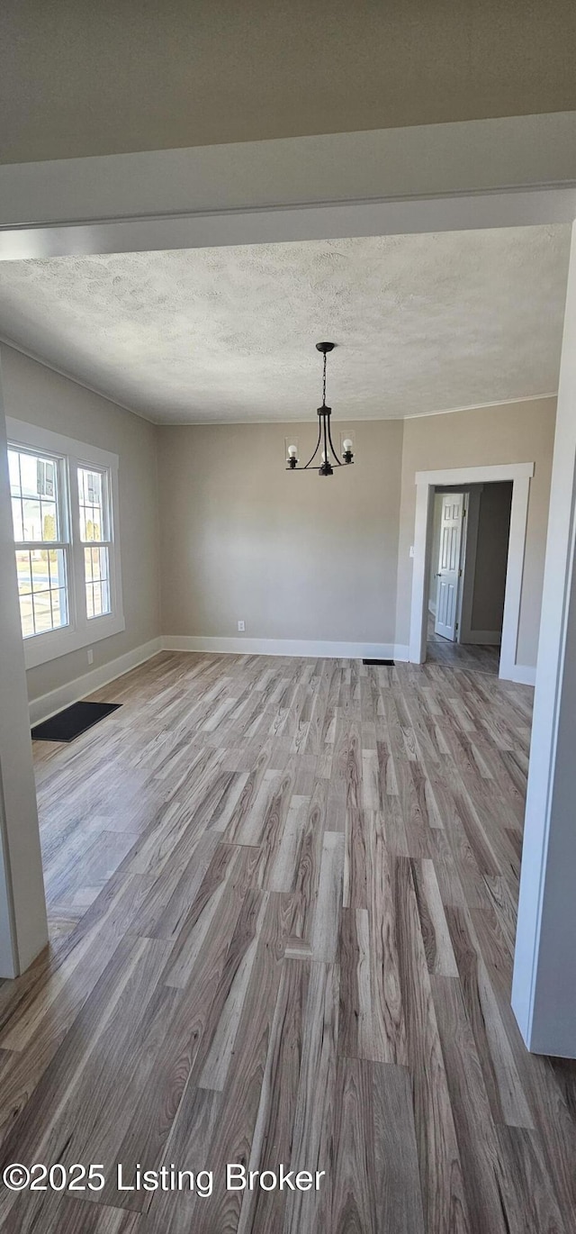 interior space with a textured ceiling, baseboards, wood finished floors, and an inviting chandelier