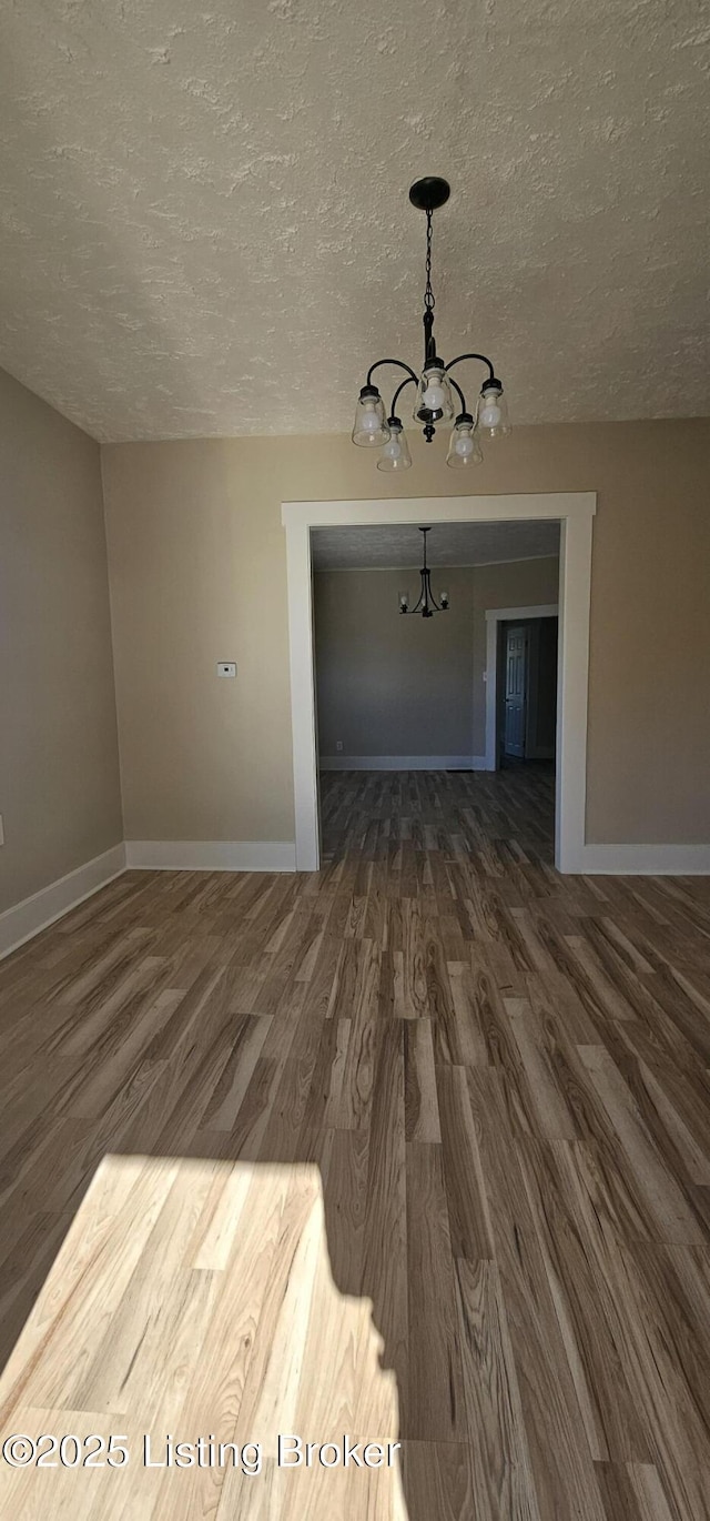 interior space featuring dark wood-style floors, a textured ceiling, and baseboards