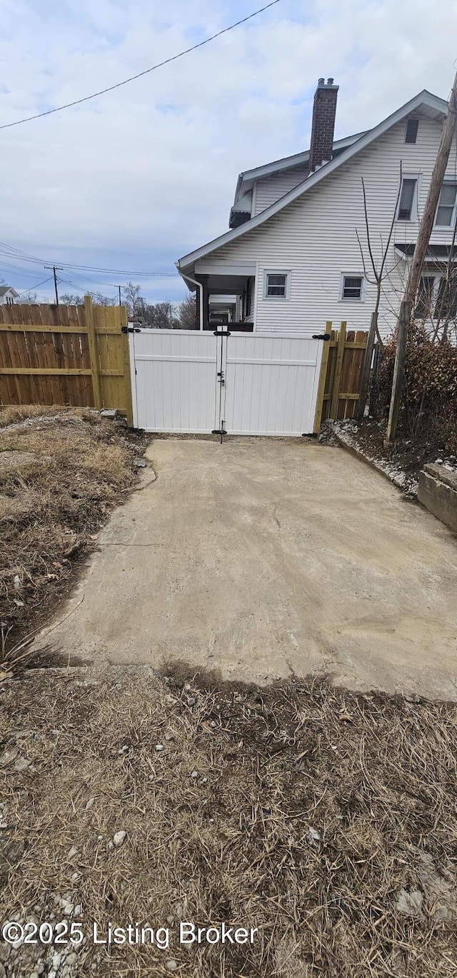 exterior space with a chimney, fence, and a gate