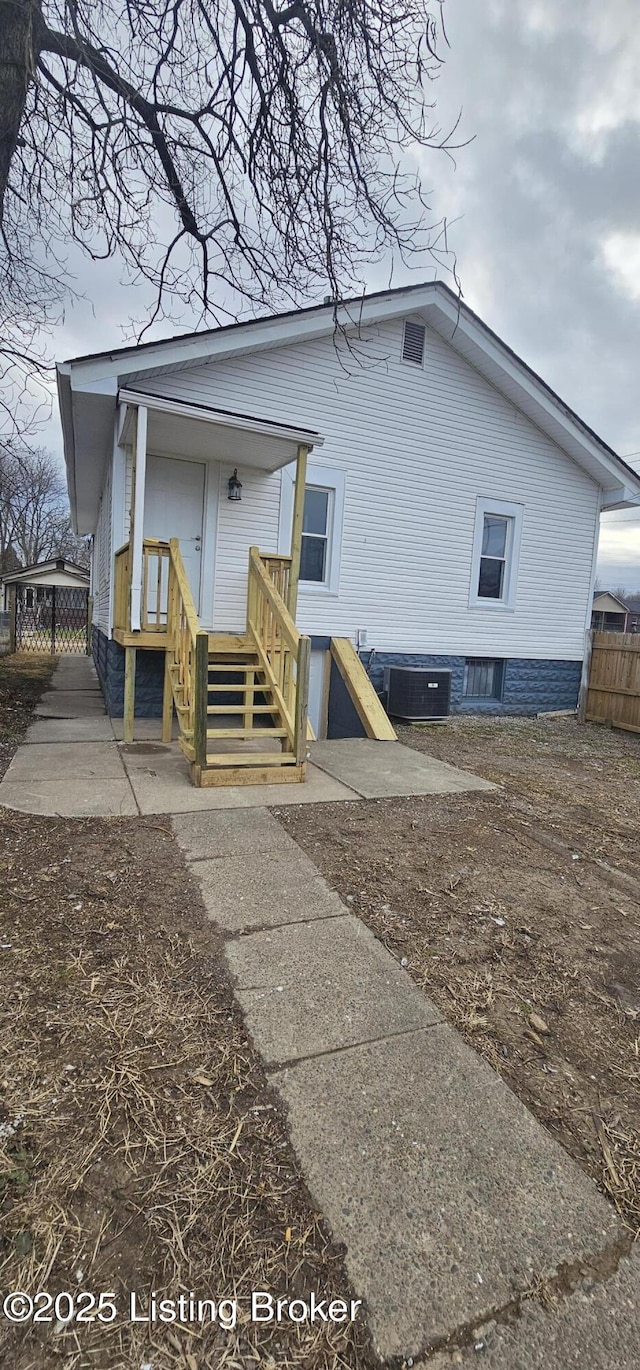 rear view of house with central air condition unit and fence