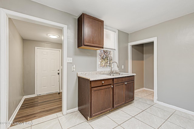 kitchen featuring light tile patterned floors, dark brown cabinets, and sink