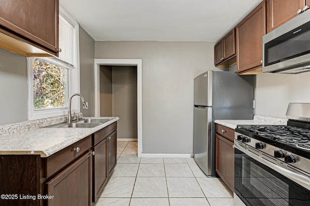 kitchen featuring sink, dark brown cabinetry, light tile patterned floors, and stainless steel appliances