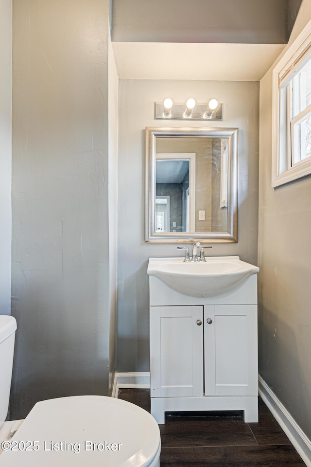 bathroom featuring toilet, vanity, and hardwood / wood-style floors