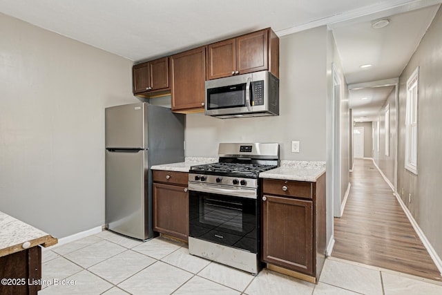 kitchen with light tile patterned floors, appliances with stainless steel finishes, and dark brown cabinets