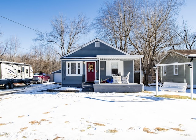 bungalow with a garage, a porch, and an outbuilding