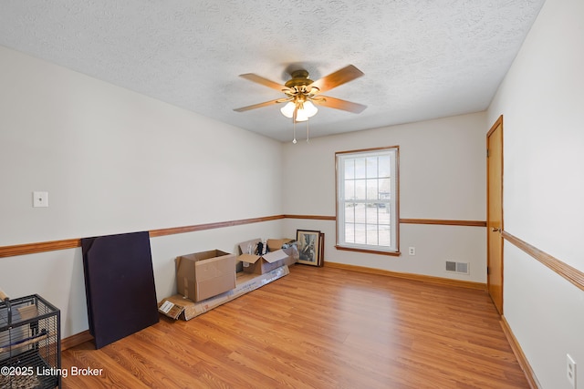 empty room featuring ceiling fan, light wood-type flooring, and a textured ceiling