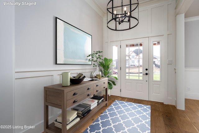 foyer entrance featuring hardwood / wood-style flooring, ornamental molding, and an inviting chandelier