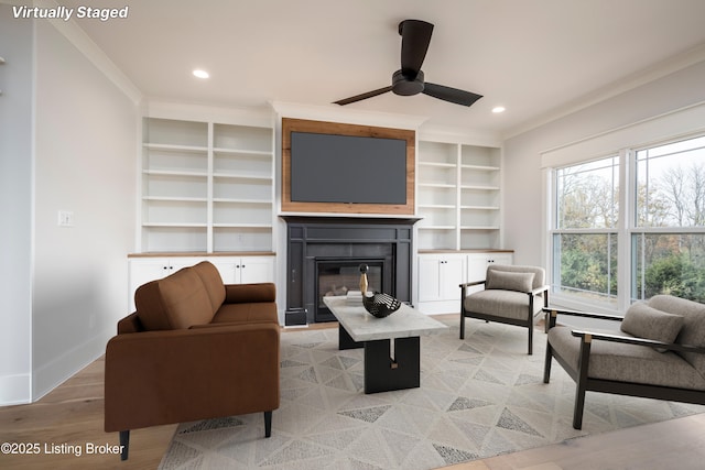 living room featuring crown molding, light hardwood / wood-style floors, and ceiling fan