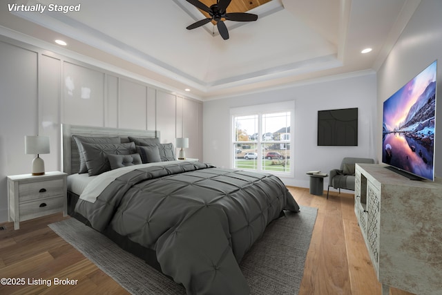 bedroom featuring hardwood / wood-style floors, crown molding, a raised ceiling, and ceiling fan