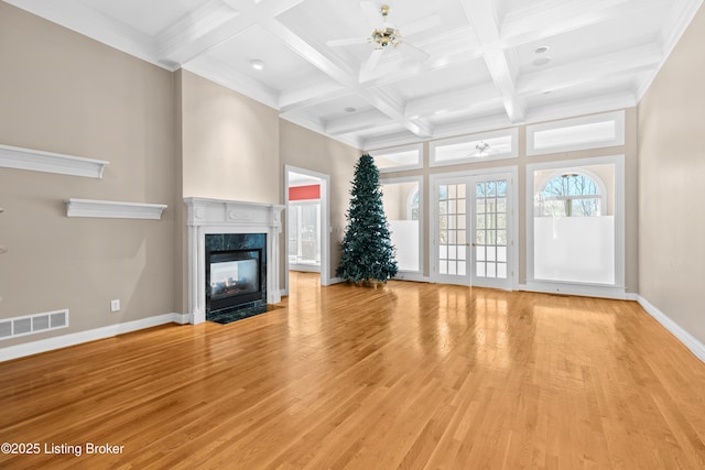 unfurnished living room featuring ceiling fan, beamed ceiling, french doors, and a fireplace