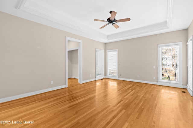 empty room featuring ceiling fan, a tray ceiling, and light hardwood / wood-style flooring