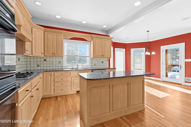 kitchen with a kitchen island, sink, hanging light fixtures, light wood-type flooring, and stainless steel appliances