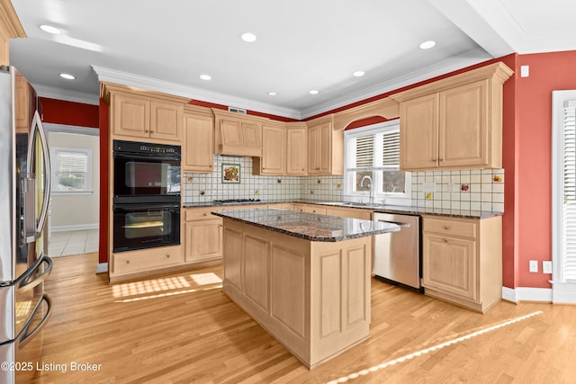 kitchen featuring light hardwood / wood-style floors, appliances with stainless steel finishes, dark stone countertops, a kitchen island, and crown molding