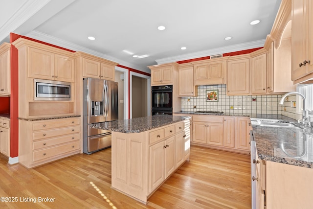 kitchen with light wood-type flooring, stainless steel appliances, dark stone countertops, and a center island