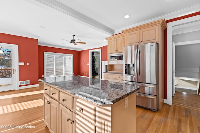 kitchen featuring dark stone countertops, light hardwood / wood-style floors, a center island, light brown cabinets, and stainless steel appliances