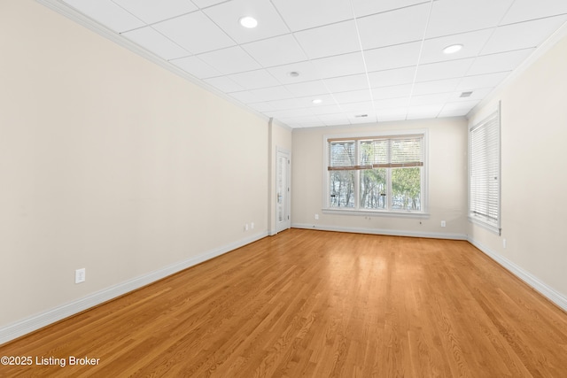 spare room featuring a drop ceiling and light hardwood / wood-style flooring