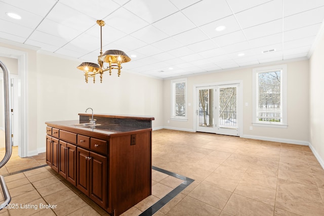 kitchen with decorative light fixtures, light tile patterned floors, an island with sink, and sink