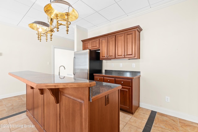 kitchen featuring light tile patterned floors, stainless steel refrigerator, a chandelier, and a kitchen island