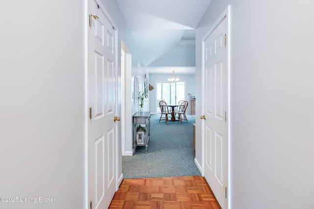 corridor with light carpet, vaulted ceiling, and a chandelier