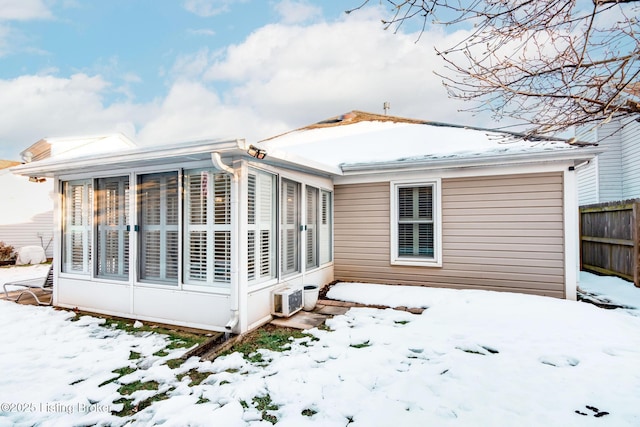 snow covered rear of property featuring a sunroom