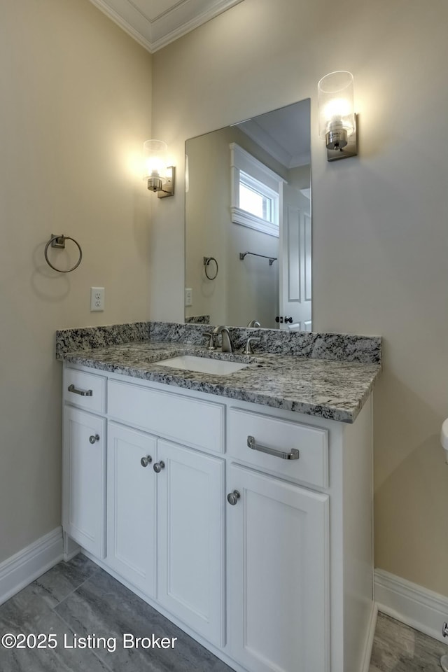 bathroom with ornamental molding, vanity, and baseboards