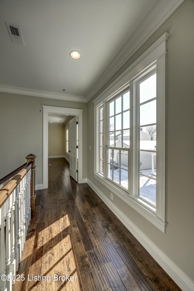 corridor featuring dark wood-style floors, visible vents, crown molding, and baseboards