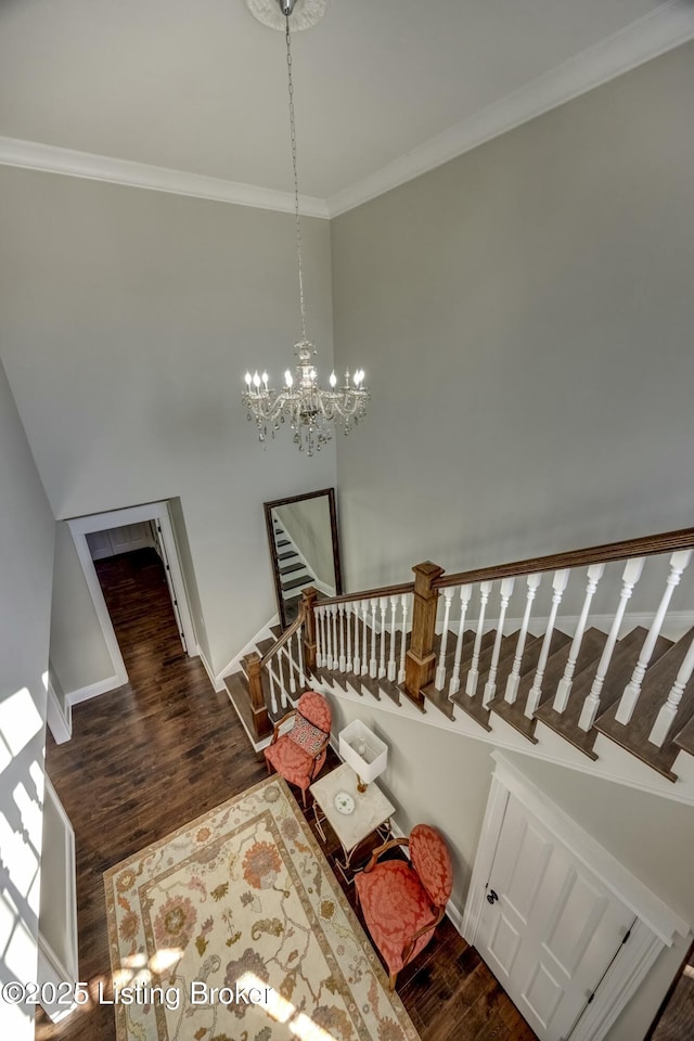 stairway with ornamental molding, a notable chandelier, baseboards, and wood finished floors