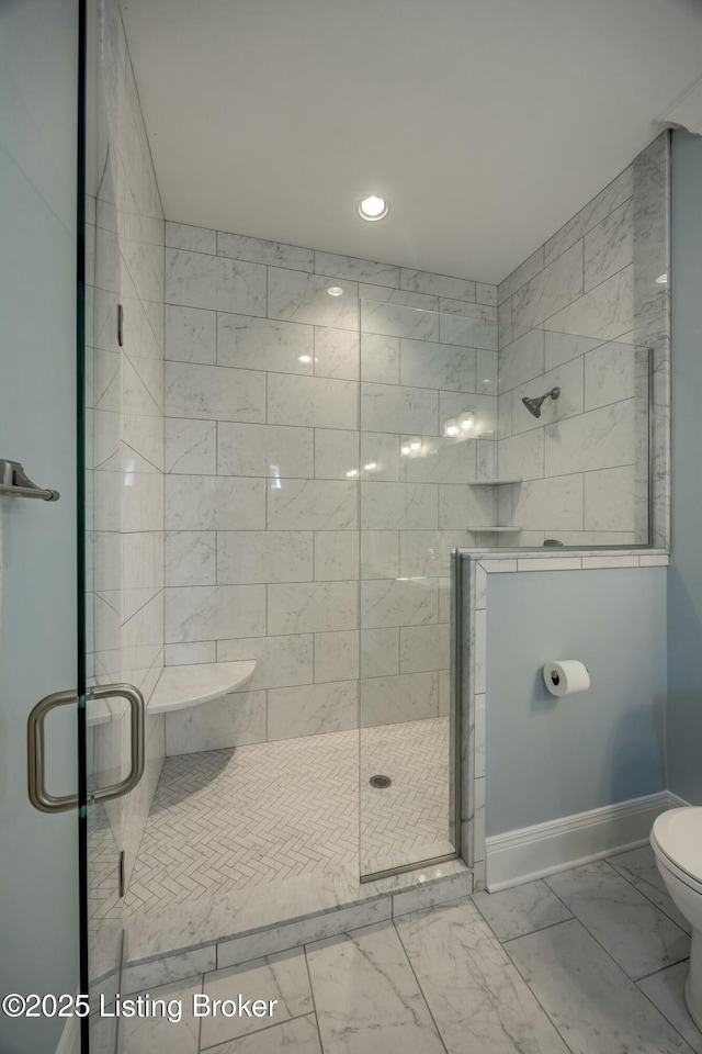 full bath with marble finish floor, a stall shower, toilet, and baseboards