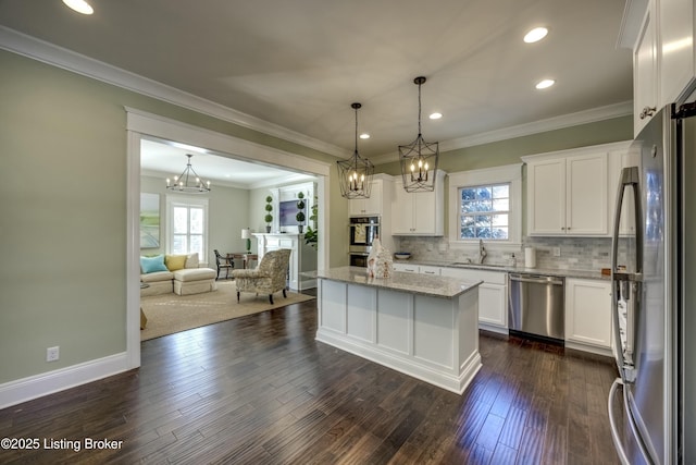 kitchen with appliances with stainless steel finishes, open floor plan, white cabinetry, and dark wood-style flooring