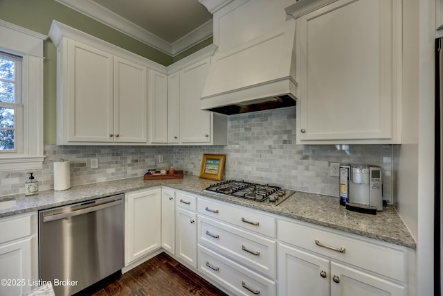 kitchen with dark wood-style flooring, crown molding, stainless steel appliances, decorative backsplash, and premium range hood