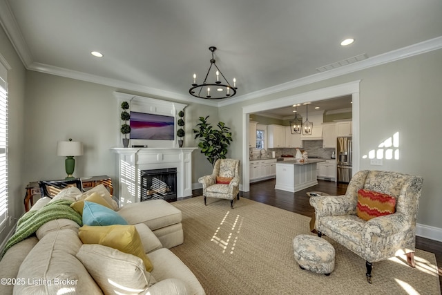 living room featuring ornamental molding, dark wood-style flooring, visible vents, and a notable chandelier