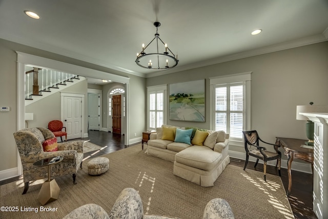 living area featuring baseboards, a notable chandelier, wood finished floors, and crown molding