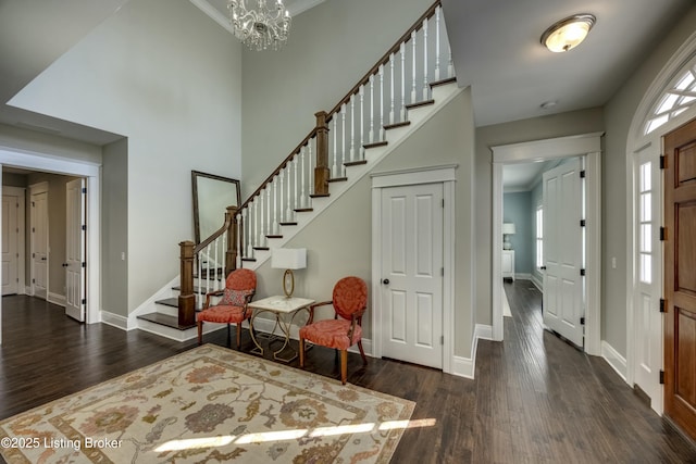 entrance foyer featuring stairway, an inviting chandelier, wood finished floors, and baseboards