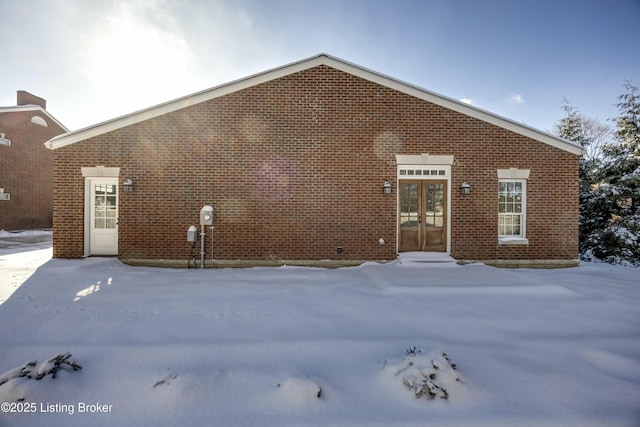 view of front facade featuring brick siding and french doors