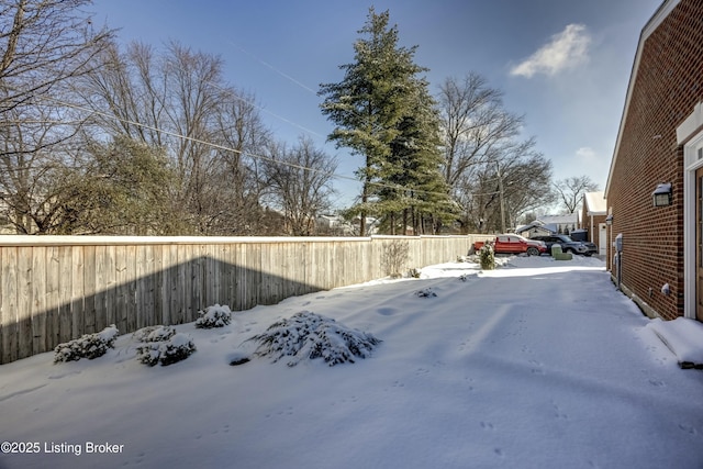 snowy yard featuring a fenced backyard