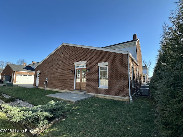 back of house with a yard, a chimney, french doors, and brick siding