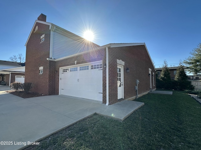 view of home's exterior with a garage, brick siding, a yard, concrete driveway, and a chimney