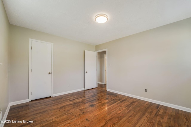 empty room with dark wood-type flooring and a textured ceiling