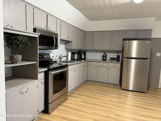 kitchen with tasteful backsplash, appliances with stainless steel finishes, sink, and gray cabinetry