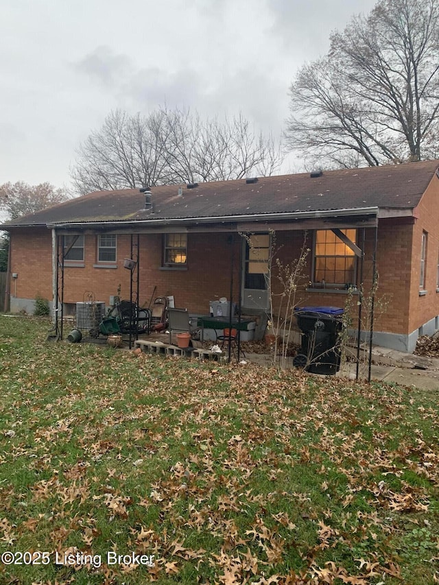 rear view of property with a yard and central air condition unit