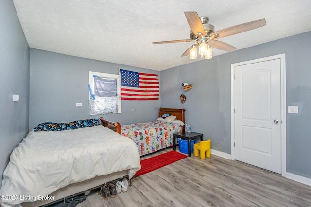 bedroom with hardwood / wood-style flooring, ceiling fan, and a textured ceiling