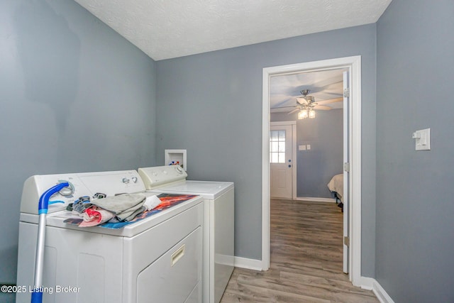 clothes washing area with ceiling fan, light hardwood / wood-style flooring, independent washer and dryer, and a textured ceiling