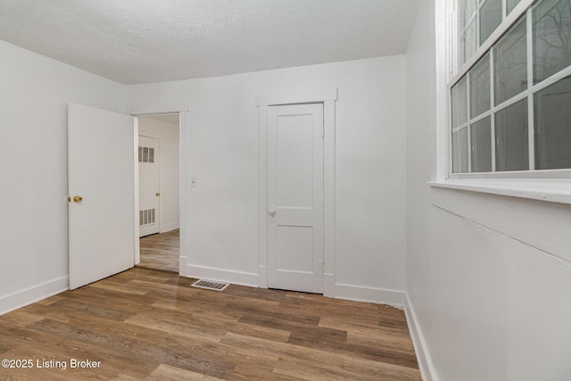 unfurnished room featuring hardwood / wood-style flooring and a textured ceiling