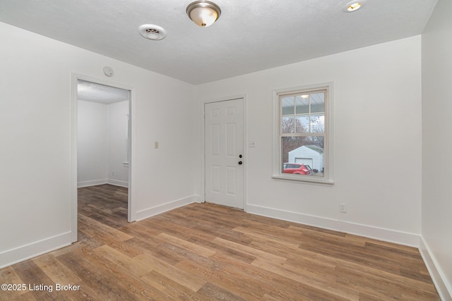 empty room featuring a textured ceiling and light hardwood / wood-style floors