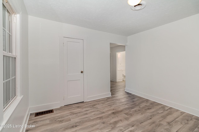 empty room with light hardwood / wood-style floors and a textured ceiling