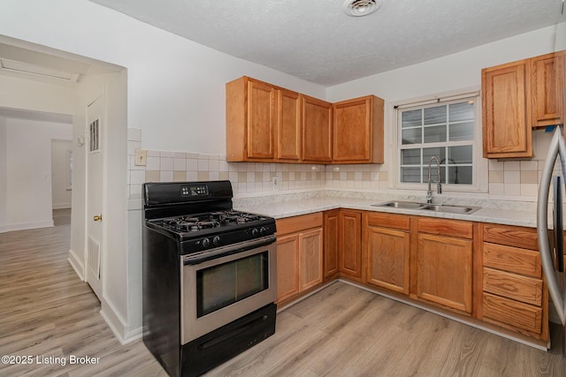 kitchen featuring tasteful backsplash, sink, light hardwood / wood-style flooring, and range with gas stovetop